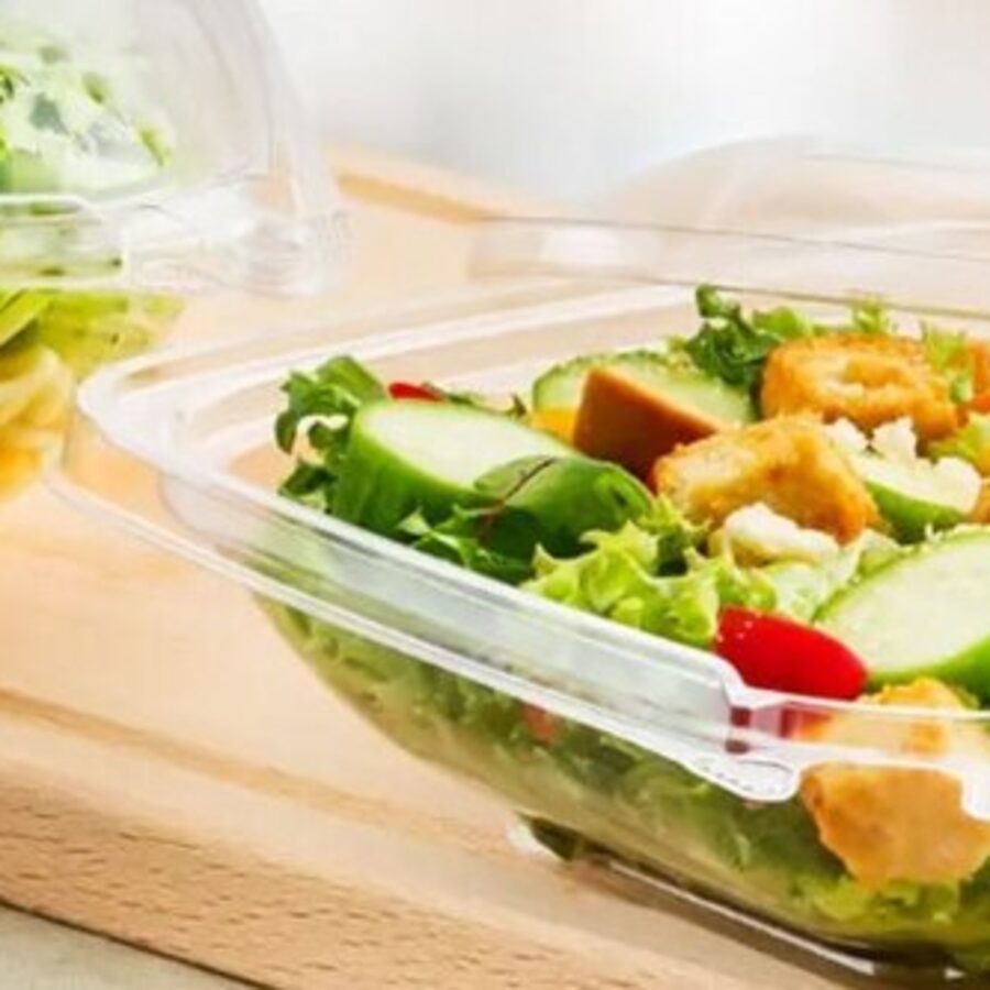 Assorted fruit and salad clamshells on a wooden board
